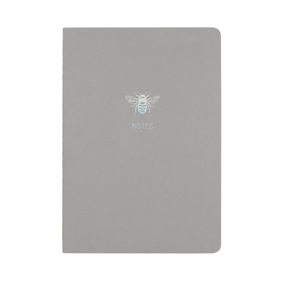 A5 SIZE NOTEBOOK BEE NOTES HOLOGRAPHIC FOILED COVER DETAIL, CARDBOARD COVER COLOR GREY, INTERIOR DOTTED, ROUNDED CORNERS, VISIBLE SINGER STITCHING ON THE SPINE, INTERIOR PAPER IVORY-COLORED 90 GMS, ACID FREE PAPER MADE IN COLOMBIA BY MAKE2D
