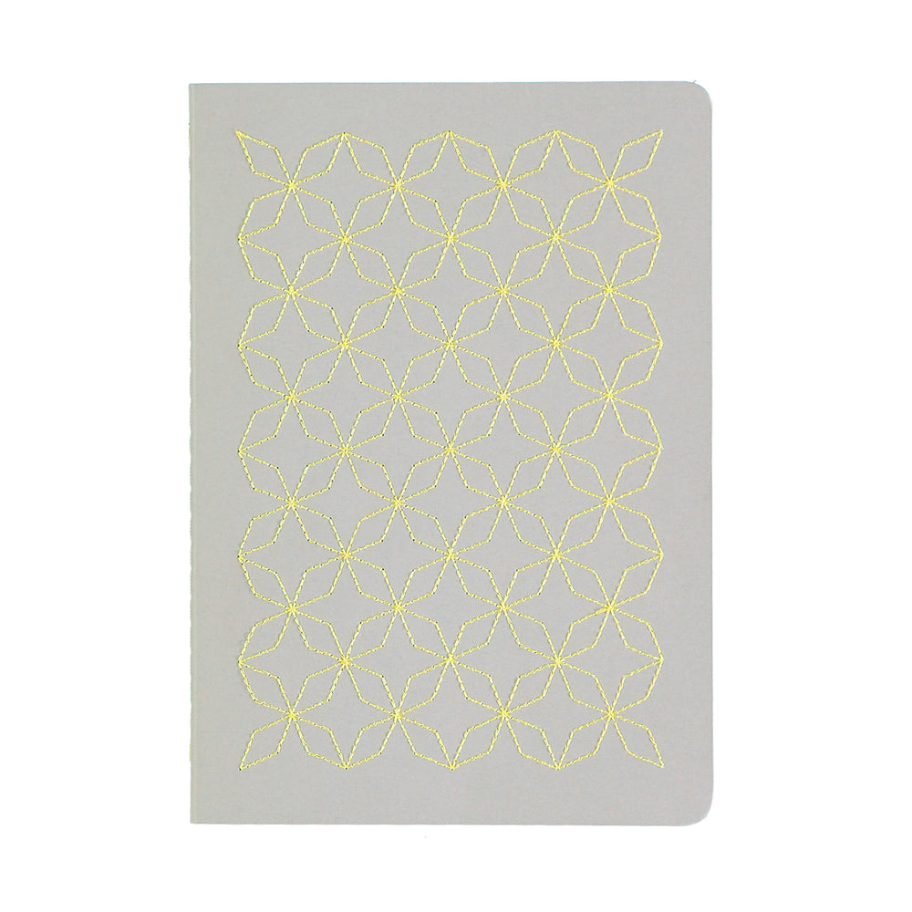 A5  SIZE NOTEBOOK EMBOROIDERED TOKYO COVER DETAIL, CARDBOARD COVER COLOR GREY, YELLOW EMBROIDERY, INTERIOR DOTTED OR RULED, ROUNDED CORNERS, VISIBLE SINGER STITCHING ON THE SPINE, INTERIOR PAPER IVORY-COLORED 90 GMS, ACID FREE PAPER BACK GOLD FOIL COVER DETAIL MADE IN COLOMBIA BY MAKE2D