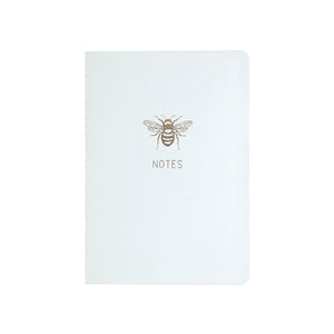 A6 POCKET SIZE NOTEBOOK BEE NOTES GOLD FOILED COVER DETAIL, CARDBOARD COVER COLOR WHITE, INTERIOR DOTTED OR RULED, ROUNDED CORNERS, VISIBLE SINGER STITCHING ON THE SPINE, INTERIOR PAPER IVORY-COLORED 90 GMS, ACID FREE PAPER MADE IN COLOMBIA BY MAKE2D