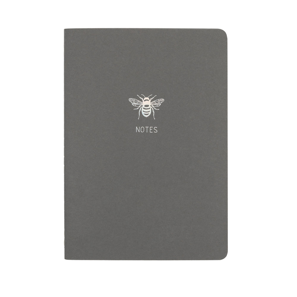 
                
                    Load image into Gallery viewer, A5 SIZE NOTEBOOK BEE NOTES HOLOGRAPHIC FOILED COVER DETAIL, CARDBOARD COVER COLOR DARK GREY, INTERIOR DOTTED, ROUNDED CORNERS, VISIBLE SINGER STITCHING ON THE SPINE, INTERIOR PAPER IVORY-COLORED 90 GMS, ACID FREE PAPER MADE IN COLOMBIA BY MAKE2D
                
            