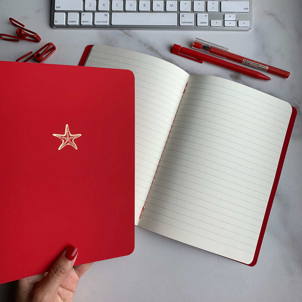 A5 SIZE NOTEBOOK STARFISH NOTES GOLD FOILED COVER DETAIL, CARDBOARD COVER COLOR RED, INTERIOR DOTTED, ROUNDED CORNERS, VISIBLE SINGER STITCHING ON THE SPINE, INTERIOR PAPER IVORY-COLORED 90 GMS, ACID FREE PAPER MADE IN COLOMBIA BY MAKE2D