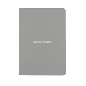 A5 SIZE NOTEBOOK THINKING PROCESS NOTES GOLD FOILED COVER DETAIL, CARDBOARD COVER COLOR SMOKE GREY, INTERIOR DOTTED, ROUNDED CORNERS, VISIBLE SINGER STITCHING ON THE SPINE, INTERIOR PAPER IVORY-COLORED 90 GMS, ACID FREE PAPER MADE IN COLOMBIA BY MAKE2D