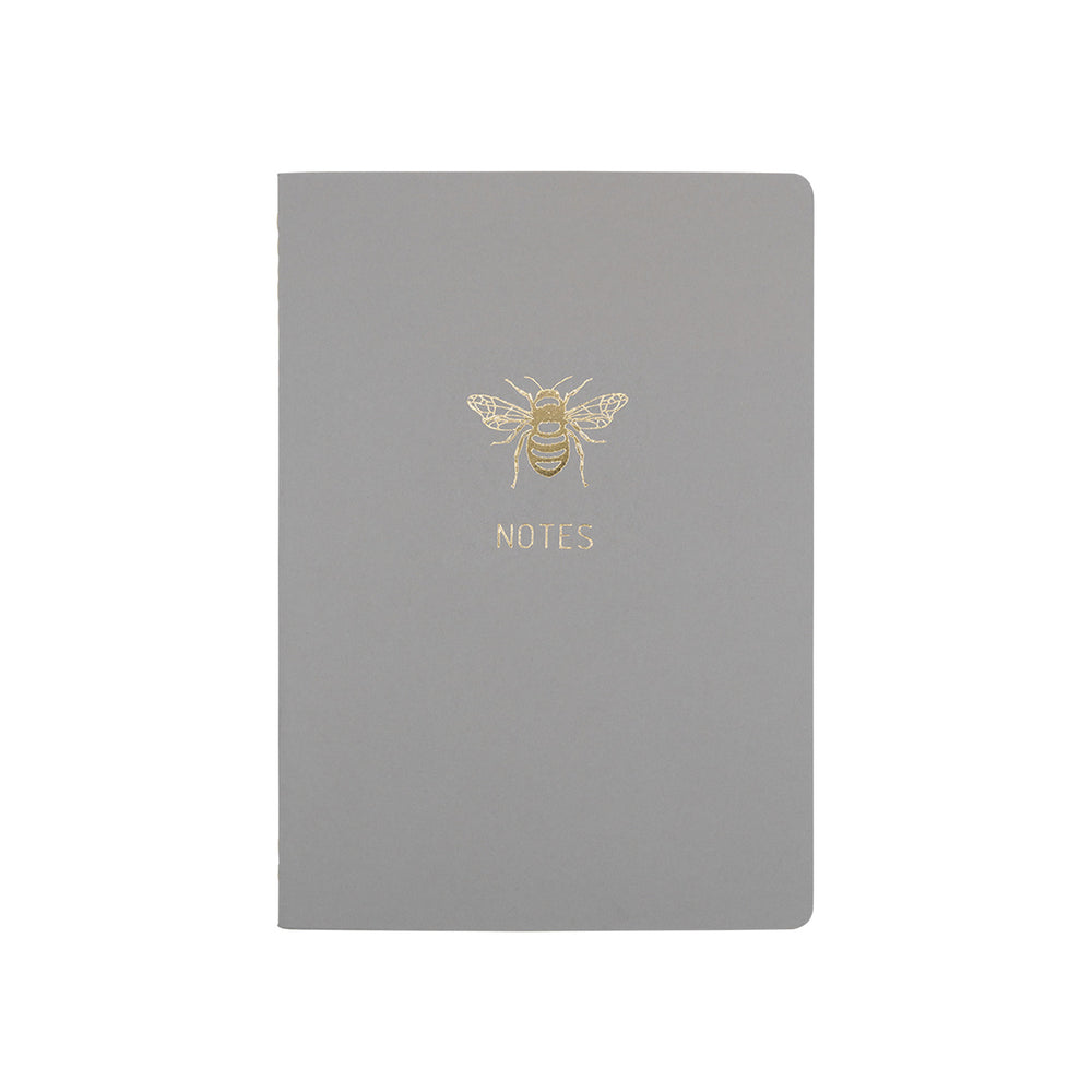A6 POCKET SIZE NOTEBOOK BEE NOTES GOLD FOILED COVER DETAIL, CARDBOARD COVER COLOR SMOKE GREY, INTERIOR DOTTED OR RULED, ROUNDED CORNERS, VISIBLE SINGER STITCHING ON THE SPINE, INTERIOR PAPER IVORY-COLORED 90 GMS, ACID FREE PAPER MADE IN COLOMBIA BY MAKE2D