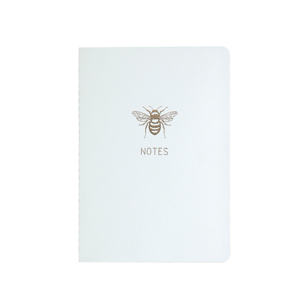 
                
                    Load image into Gallery viewer, A6 POCKET SIZE NOTEBOOK BEE NOTES GOLD FOILED COVER DETAIL, CARDBOARD COVER COLOR WHITE, INTERIOR DOTTED OR RULED, ROUNDED CORNERS, VISIBLE SINGER STITCHING ON THE SPINE, INTERIOR PAPER IVORY-COLORED 90 GMS, ACID FREE PAPER MADE IN COLOMBIA BY MAKE2D
                
            